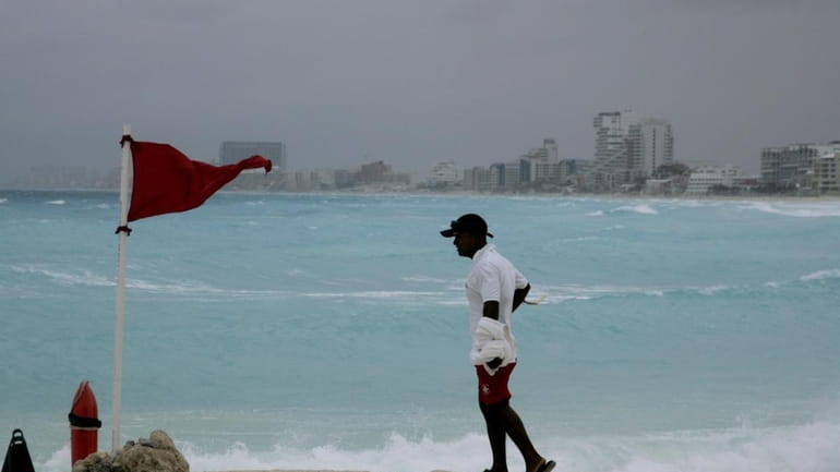 A lifeguard stands next to a red flag meaning high...