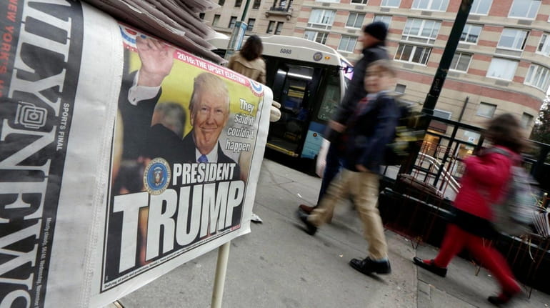 Pedestrians walk past headlines announcing the victory of President-elect Donald...