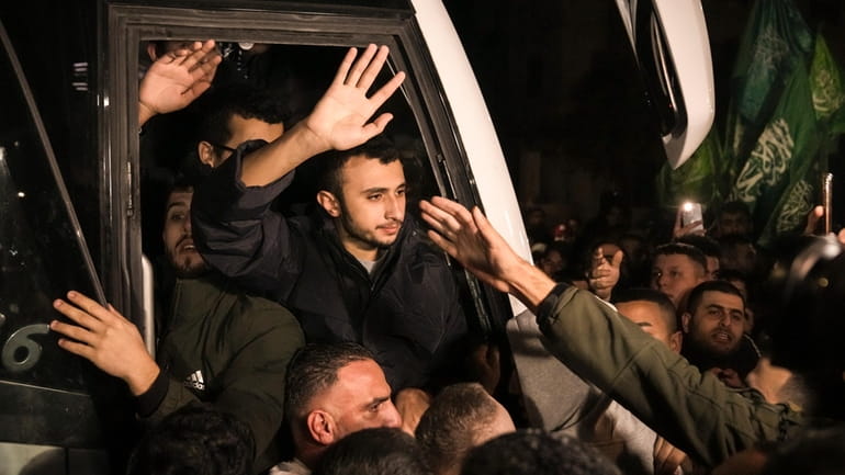 Men wave after being released from prison by Israel, Thursday,...