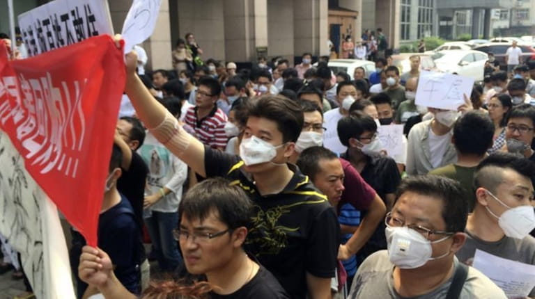 Residents, some wearing masks, hold banners and placards as they...