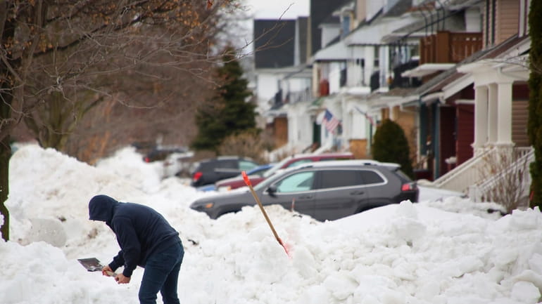 A person removes snow from the front of his driveway...