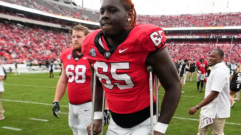 Georgia offensive lineman Amarius Mims uses crutches to leave the...