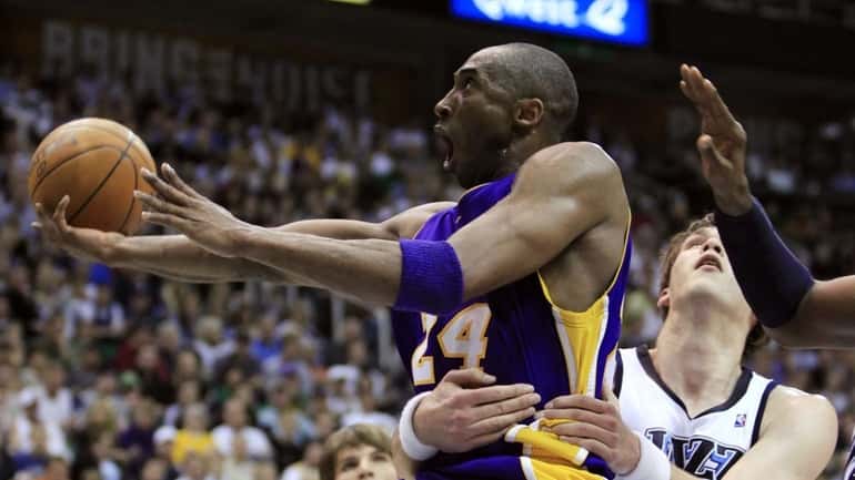 Los Angeles Lakers guard Kobe Bryant (24) is held by...