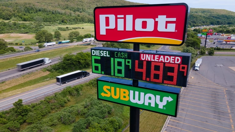 Trucks and cars drive by a Pilot Travel Center sign...