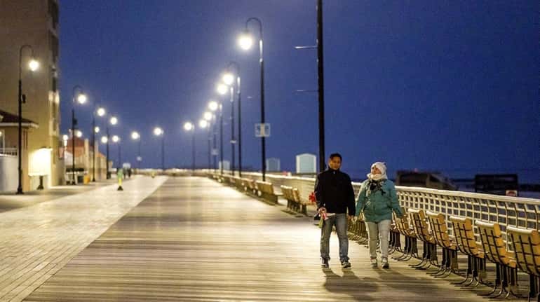 A couple strolls on the boardwalk in Long Beach, Sunday,...