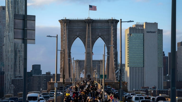 People walk on the Brooklyn Bridge at sunset, Nov. 18,...