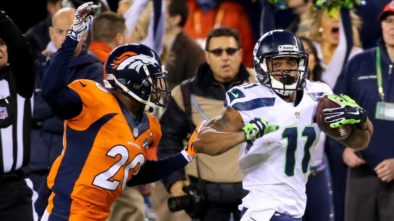 Seahawks wide receiver Percy Harvin runs the ball while being...