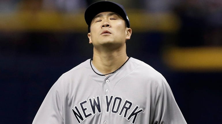 Yankees pitcher Masahiro Tanaka reacts after his throwing error on...
