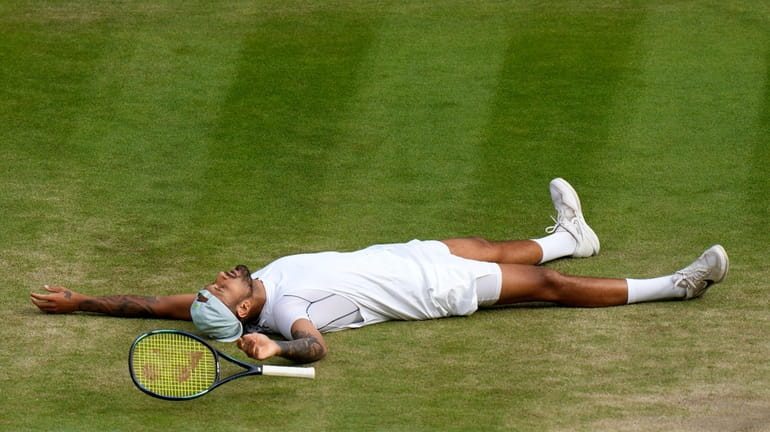 Australia's Nick Kyrgios lies on the ground after defeating Chile's...