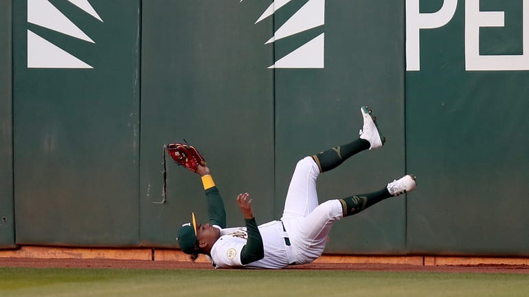 Oakland Athletics' Cristian Pache falls after catching a ball hit...
