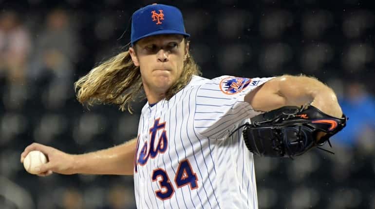 Mets pitcher Noah Syndergaard delivers a pitch to a Braves batter...