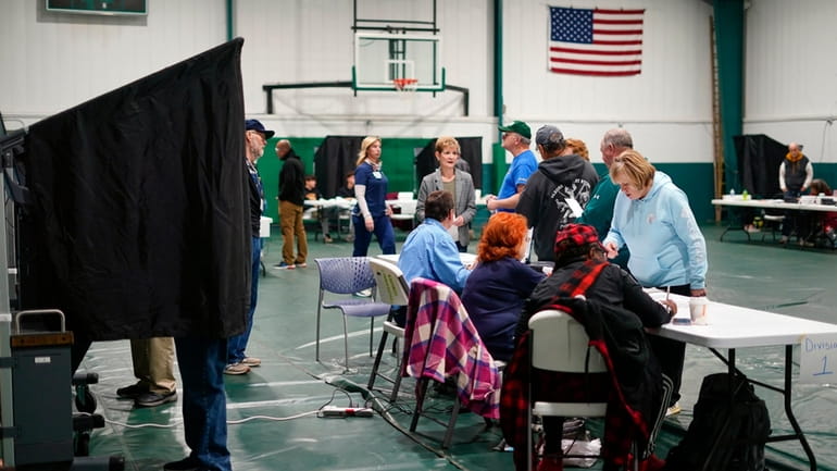 Voters check in at their polling place before casting their...