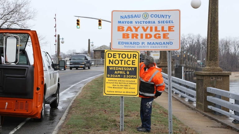 A worker attaches a sign that says the Bayville Bridge...