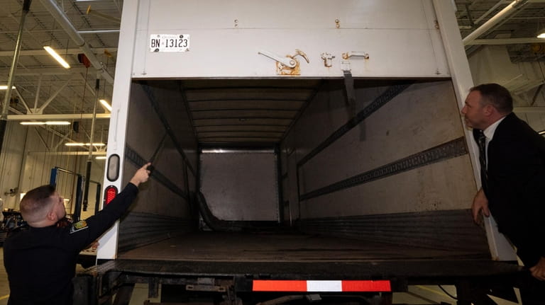 Police officers open the back of a recovered truck during...