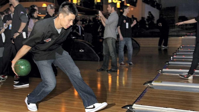 NY Knick Jeremy Lin rolls a ball as Knicks players,...