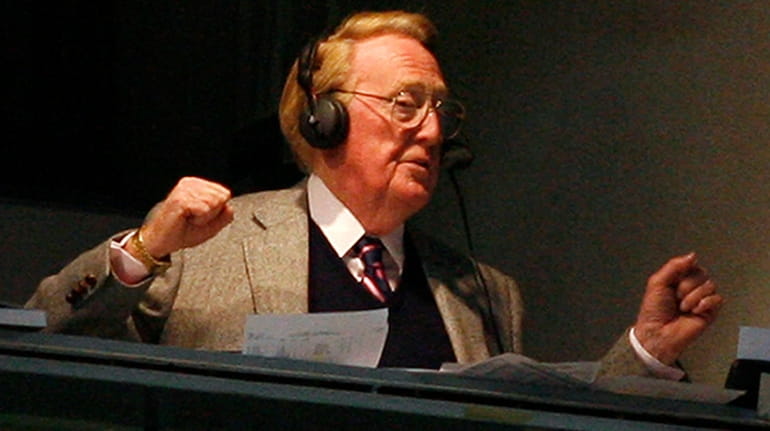 Vin Scully broadcasts from a booth at Dodger Stadium during...