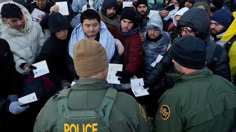Border Patrol agents ask asylum-seeking migrants to line up in...