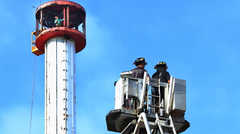 Firemen look on as workers disassemble the Astrotower in Coney...