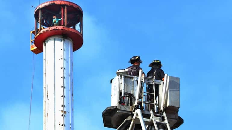 Firemen look on as workers disassemble the Astrotower in Coney...