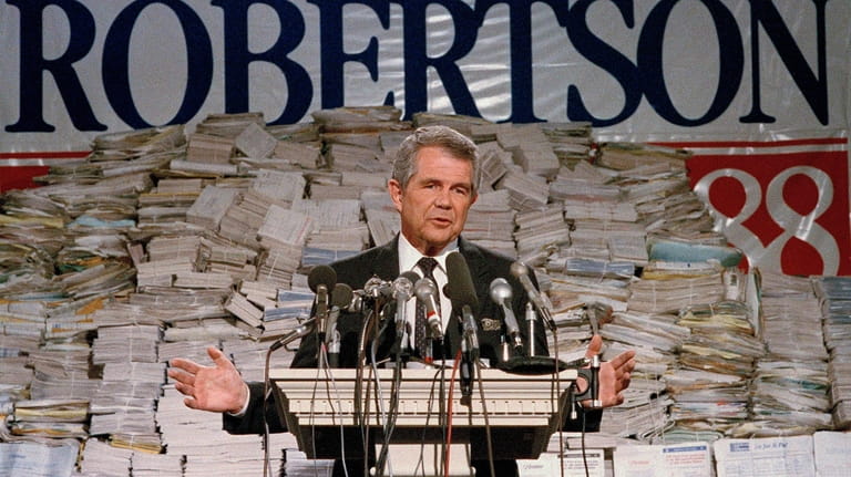 Pat Robertson, stands in front of stacks of signatures as...