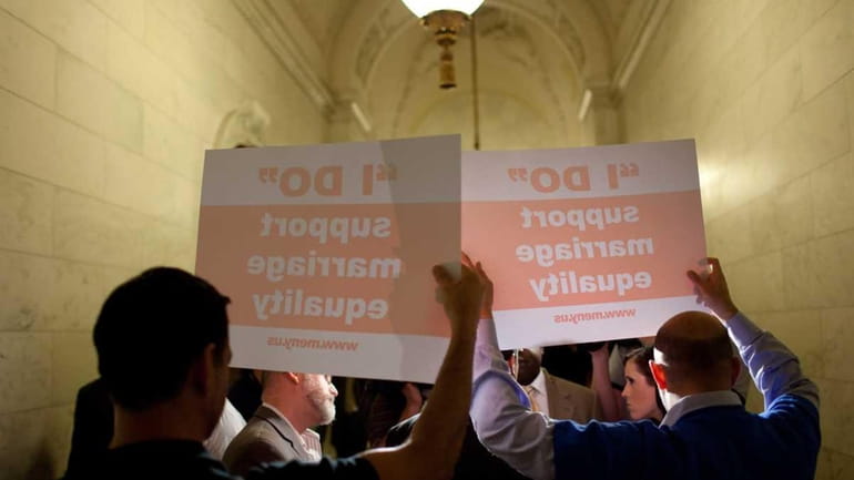 Supporters of a sex marriage bill hold signs as Senators...