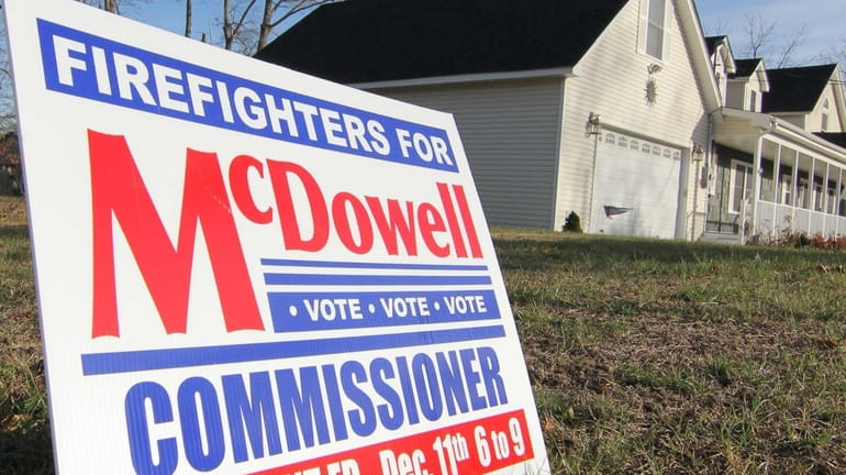 A sign for McDowell for Commissioner sits on a lawn...