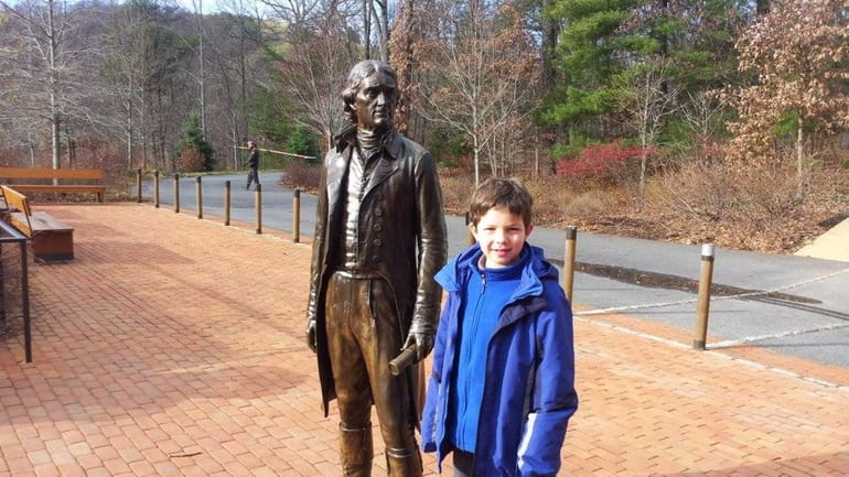 Harrison Kellogg McKenna stands alongside a statue of Thomas Jefferson...