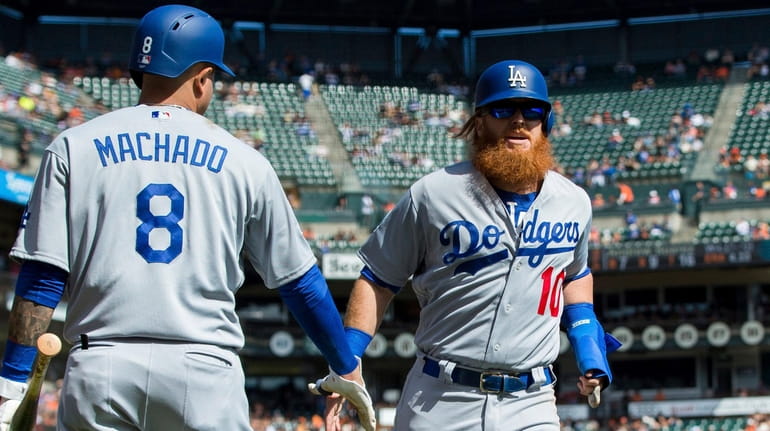 The Dodgers' Justin Turner celebrates with Manny Machado after scoring...