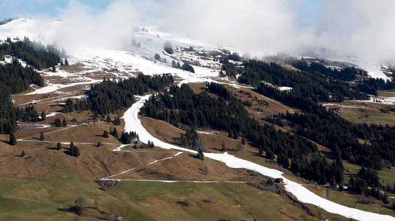 A strip of snow makes a ski slope in Saalbach,...