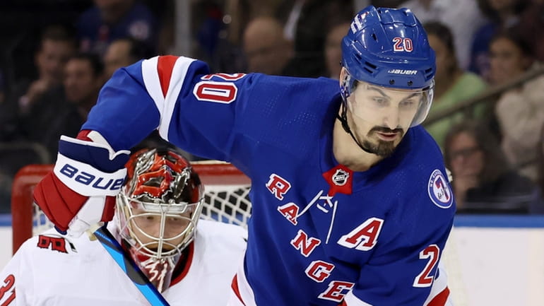 Rangers left wing Chris Kreider plays the puck in front of...