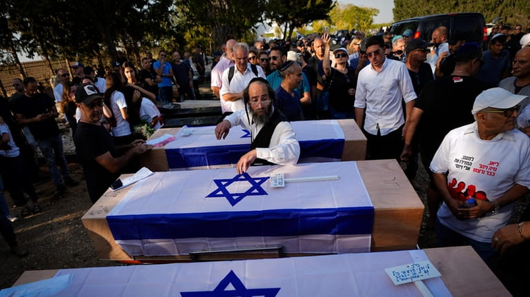 Mourners gather around the coffins of British-Israelis Lianne Sharabi and...