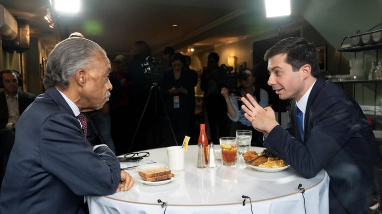 Democratic presidential candidate Pete Buttigieg, right, speaks with the Rev....