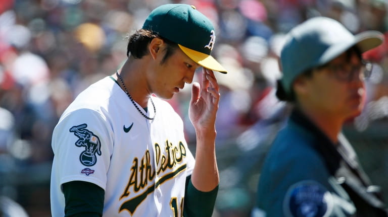Oakland Athletics starting pitcher Shintaro Fujinami, left, is taken out...