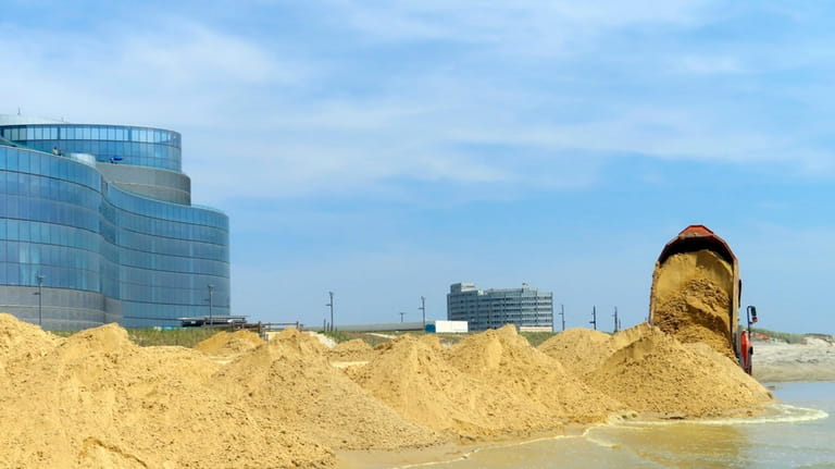 A load of sand is dumped on the beach in...