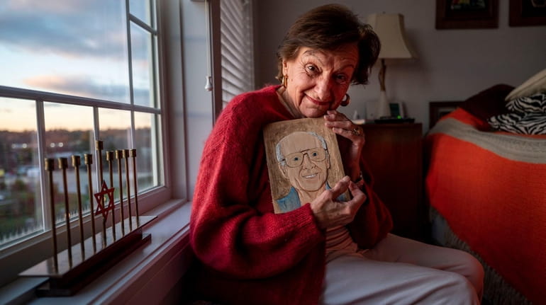 Marsha Elowsky, with a wood carving depicting her late husband,...