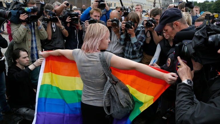A gay rights activist stands with a rainbow flag, in...