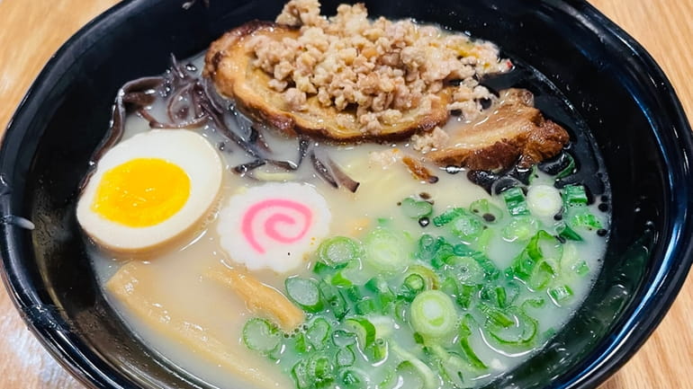 A bowl of tonkotsu, its chashu topped with minced pork, at...