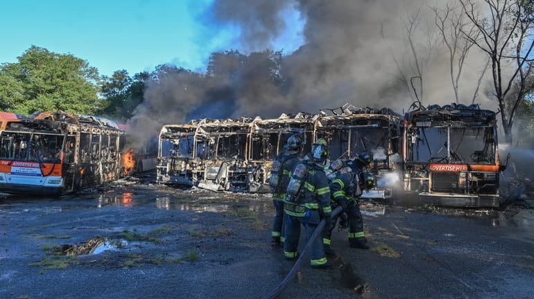 Firefighters direct water at burning buses in Cedar Creek Park in...