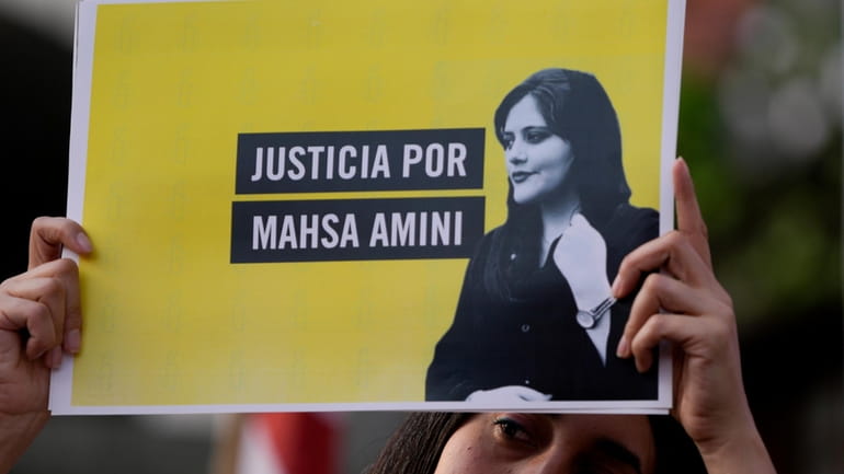 A woman holds a sign that reads in Spanish "Justice...
