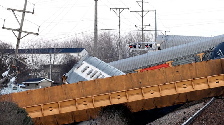Multiple cars of a Norfolk Southern train lie toppled on...