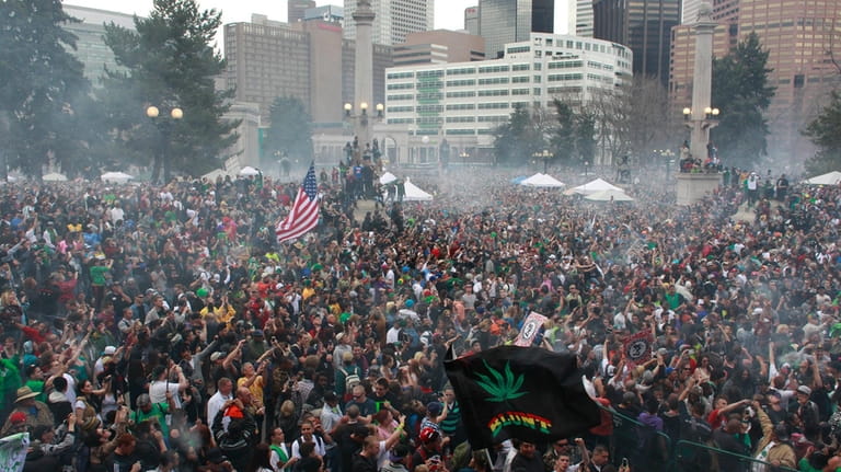 Members of a crowd numbering tens of thousands smoke marijuana...