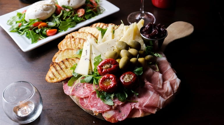 A charcuterie board for two with olives, peppers, prosciuto, sopresatta,...