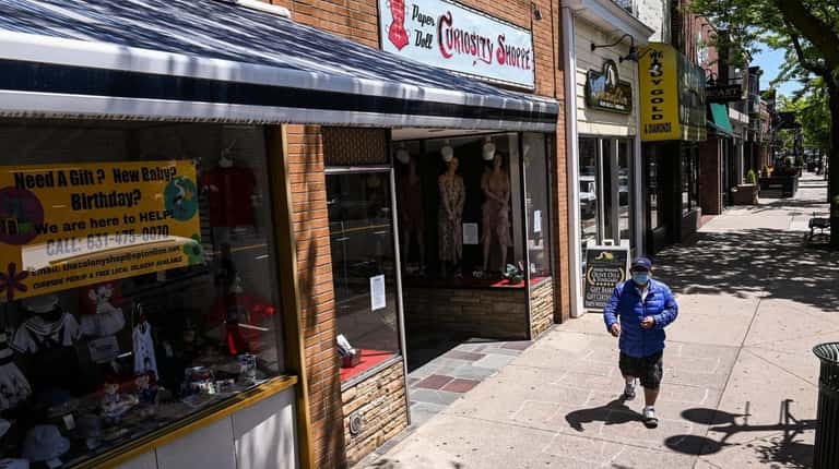 People walk past the Colony Shop on Main Street in Patchogue...