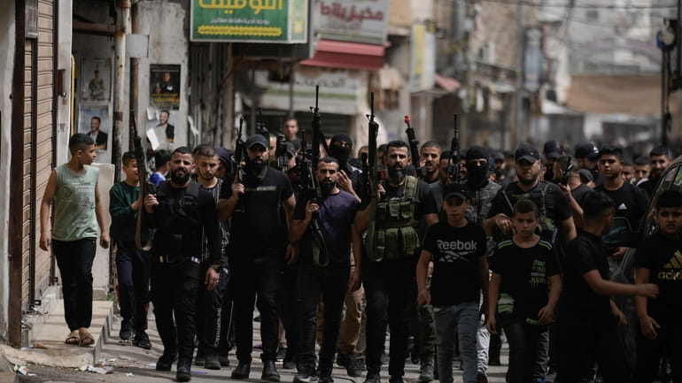 Palestinian gunmen march during the funeral of three Palestinian militants,...