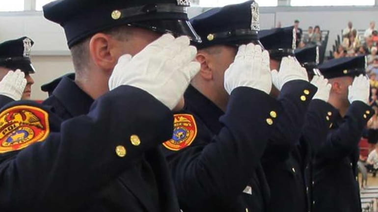 Suffolk County Police Officers salute during their graduation ceremony from...