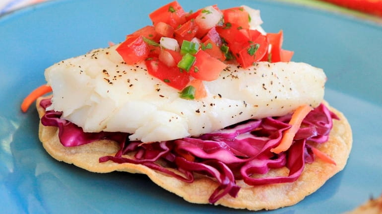 Baked corn tortillas topped with cabbage salad, baked cod and...