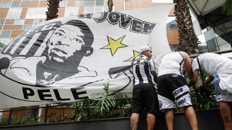 Santos soccer team supporters secure a banner with the image...