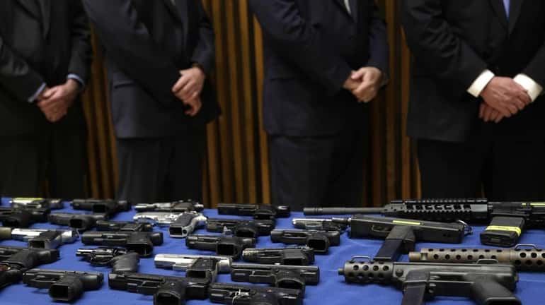 Police officers stand next to a table of guns on...