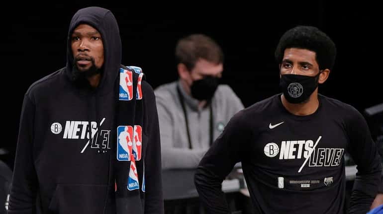 The Nets' Kevin Durant, left, stands next to teammate Kyrie...