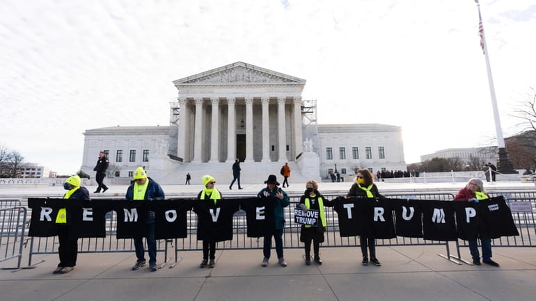 Protesters hold their banners in front of the U.S. Supreme...